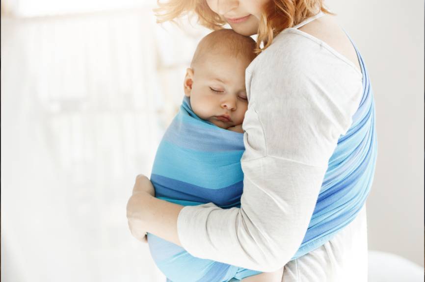 Baby in blauwe draagzak bij moeder